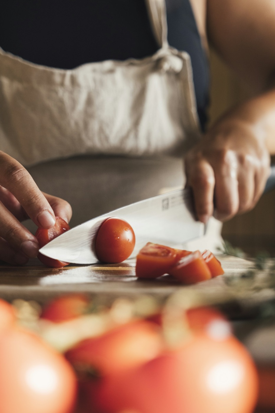 Mains qui coupent des tomates fraîches sur une planche